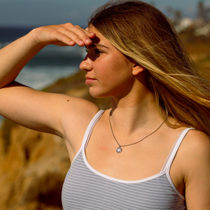 model wearing small silver black st. christopher at beach 